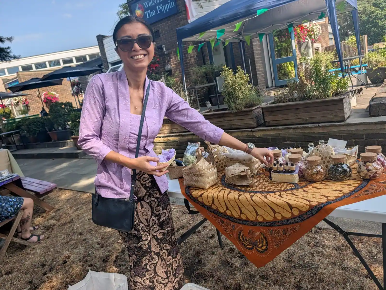 Dini in a lilac kebaya beside the Mandi7 stall