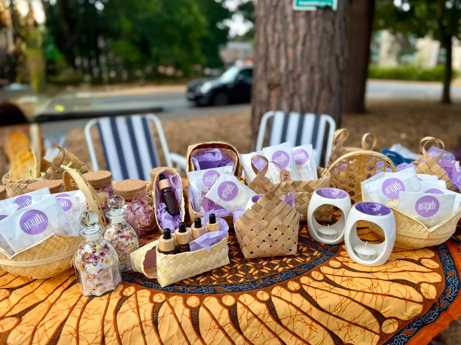 The full Mandi7 table under the pines: besek baskets, oils, bath salts and ceramic burners