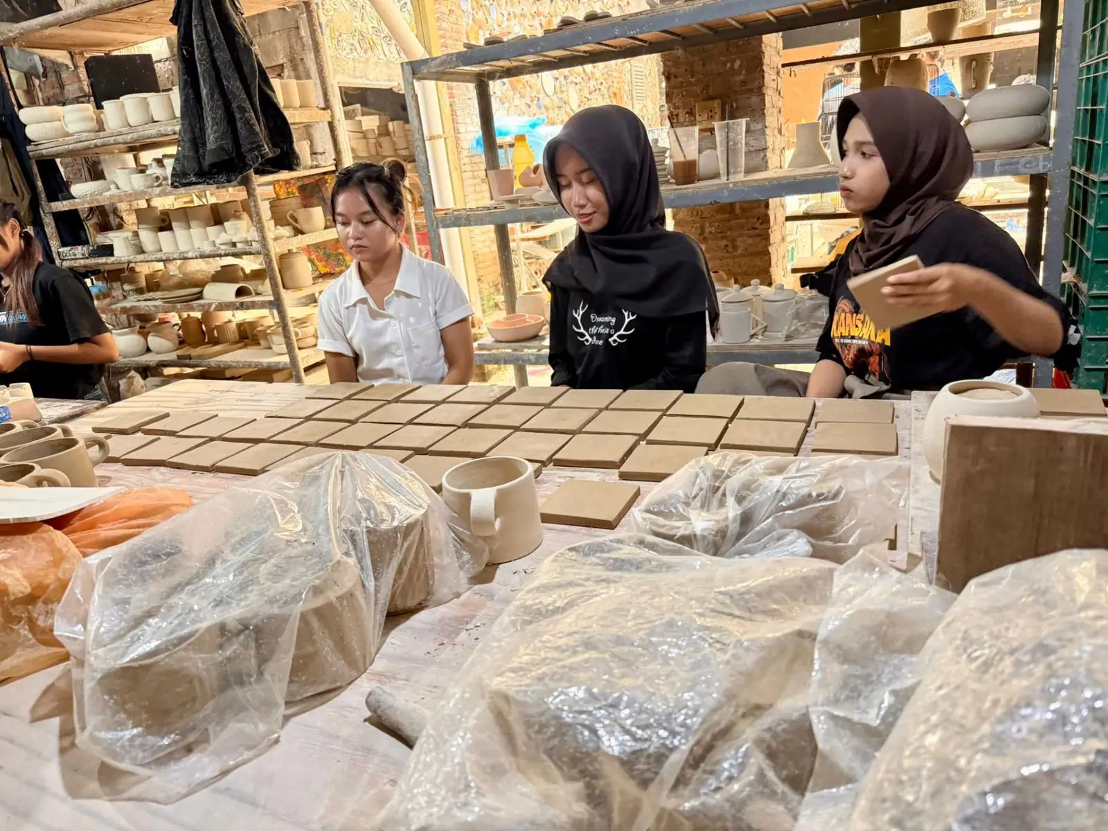 Young workers shaping clay tiles at the workshop